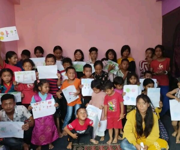 Vital Solutions Work in Nepal, large group of children in Nepal holding up artwork/signs, indoors.