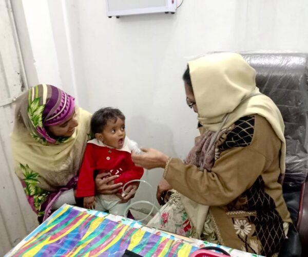 Vital Solutions Work in Pakistan, Vital Solutions doctor examining a child, indoors.