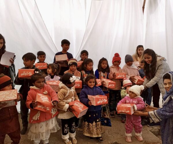Vital Solutions Work in Pakistan, group of children holding care packages, indoors.